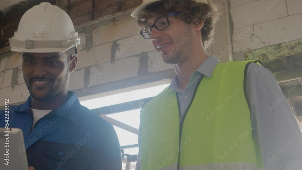 Team architect two young man discussing and looking digital tablet for inspection construction site, foreman and worker examining infrastructure of house development for planning project together. Team architect two young man discussing and looking digital tablet for inspection construction site, foreman and worker examining infrastructure of house development for planning project together.