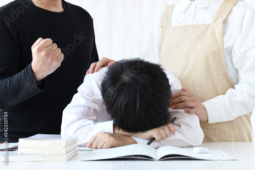 Canvastavla 机に頭を伏せる子供と励ます母親と父親