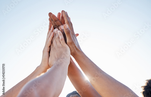 Hands, high five and collaboration on sports goal with friends in trust huddle for motivation, support and energy. Hand, fitness and people in team for exercise, workout and training against blue sky photo