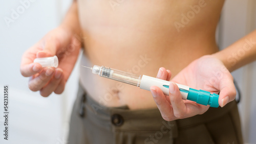 Close up woman using IVF treatment injection on belly to prepare reproductive fertility , Ovulation stimulation .