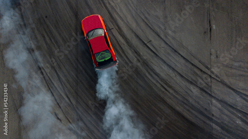 Foto Aerial top view car drifting, Race drift car with lots of smoke from burning tires on speed track, Two car drifting battle on asphalt race track, Two drift cars battle with smoke from burned tire