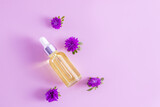 a glass dropper bottle with a serum for the face or a cosmetic product for the care of anti-aging facial skin. lilac background. top view.