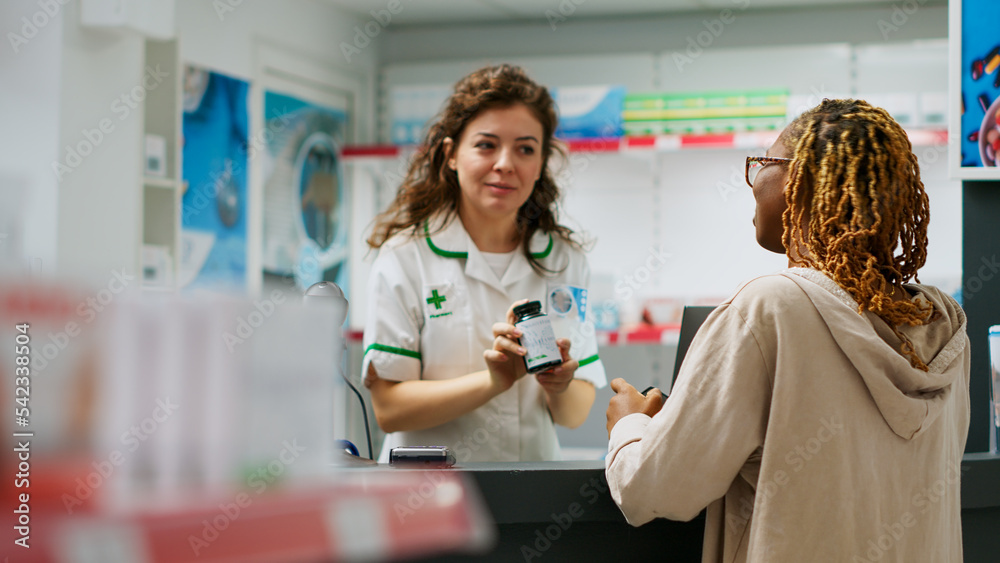 Obraz premium African american person asking pharmacist about prescription treatment in bottle of pills to buy from pharmacy shop. Medical worker serving woman with pharmaceutical products and medication.