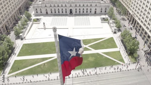 Aerial enormes flag with government palace in the back with people walking and surrounded by buildings in Santiago de Chile photo