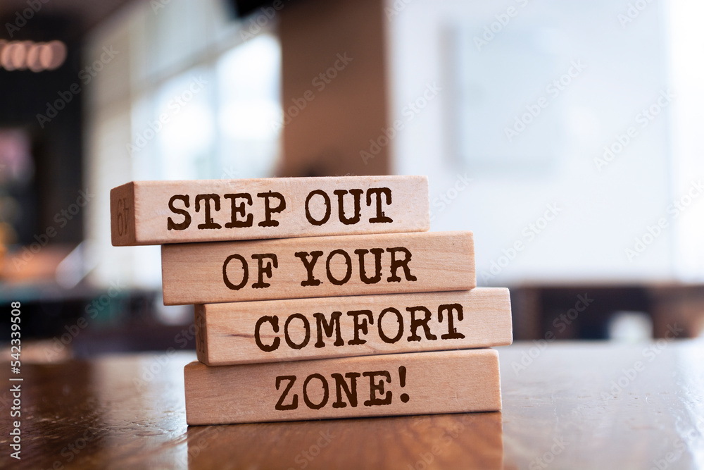 Wooden blocks with words 'Step out of your comfort zone'.