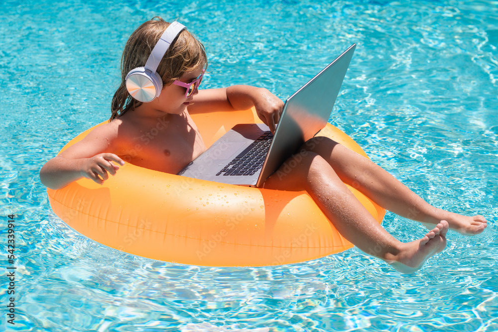 Business summer travel. Kids working with laptop on summer vacation holidays. Little freelancer using computer, remote working in swimming pool.