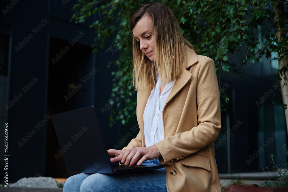 Woman remotely working, sitting on bench at city street and using laptop. Female freelancer work online, typing on laptop keyboard Woman remotely working, sitting on bench at city street and using laptop. Female freelancer work online, typing on laptop keyboard