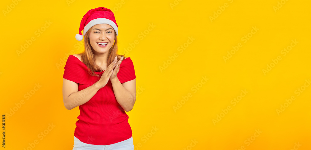 Smiling young woman wearing Christmas hat and applauding after presentation in a conference on yellow background Smiling young woman wearing Christmas hat and applauding after presentation in a conference on yellow background