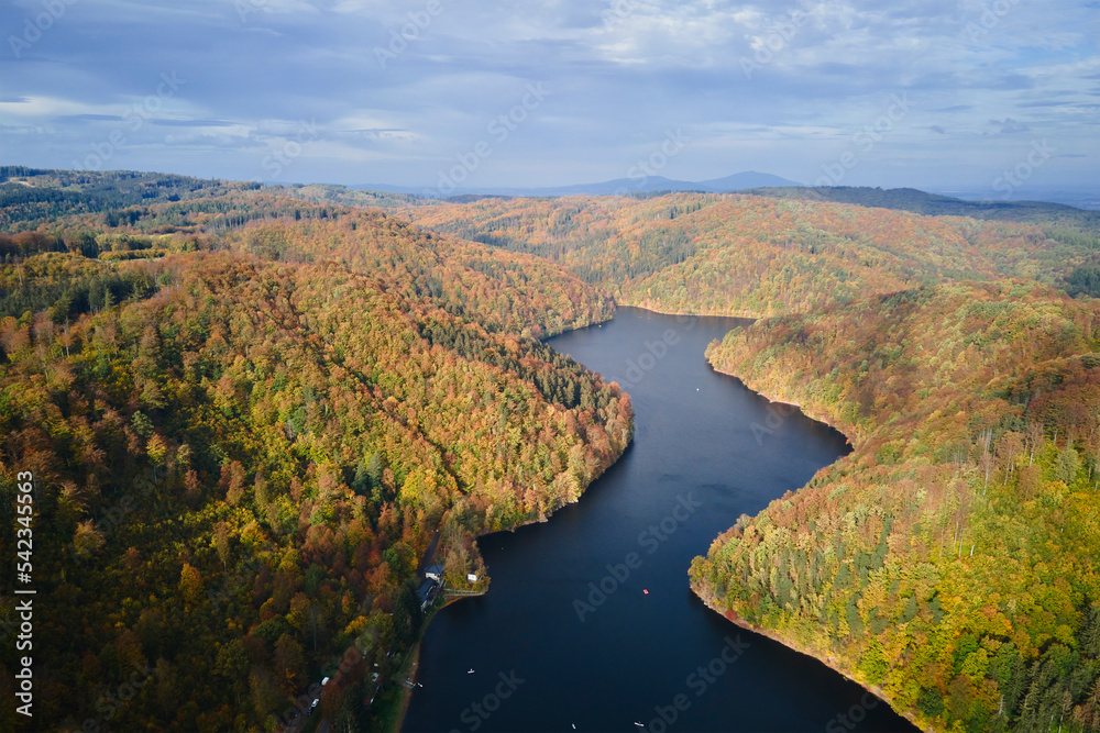 Aerial top view of amazing autumn landscape with mountains covered with forest and river. Beautiful nature landscape at fall season