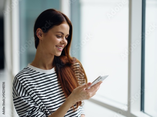 Woman smile talking on the phone video call online communication, woman at the window in the office in the city