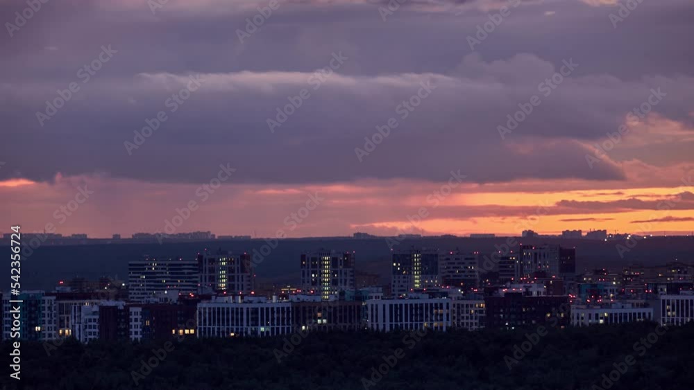Illuminated windows of city buildings at dusk, night cityscape. Timelapse of cloudy sky and evening city Illuminated windows of city buildings at dusk, night cityscape. Timelapse of cloudy sky and evening city