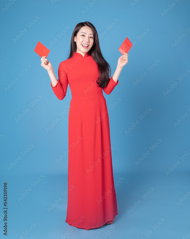 Full length image of young Vietnamese woman wearing red ao dai on background Full length image of young Vietnamese woman wearing red ao dai on background