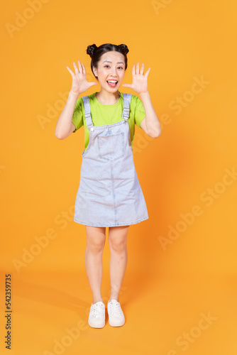 Full length image of young Asian woman standing on background