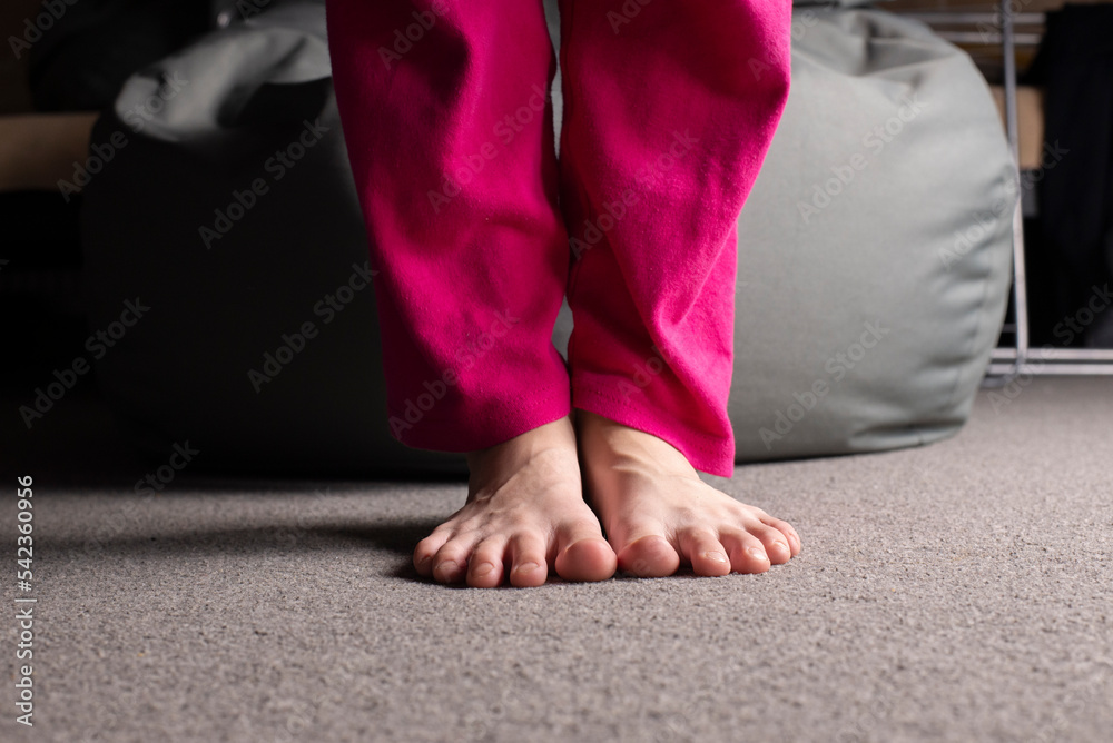 Bare feet of a girl standing on the floor. Human foot