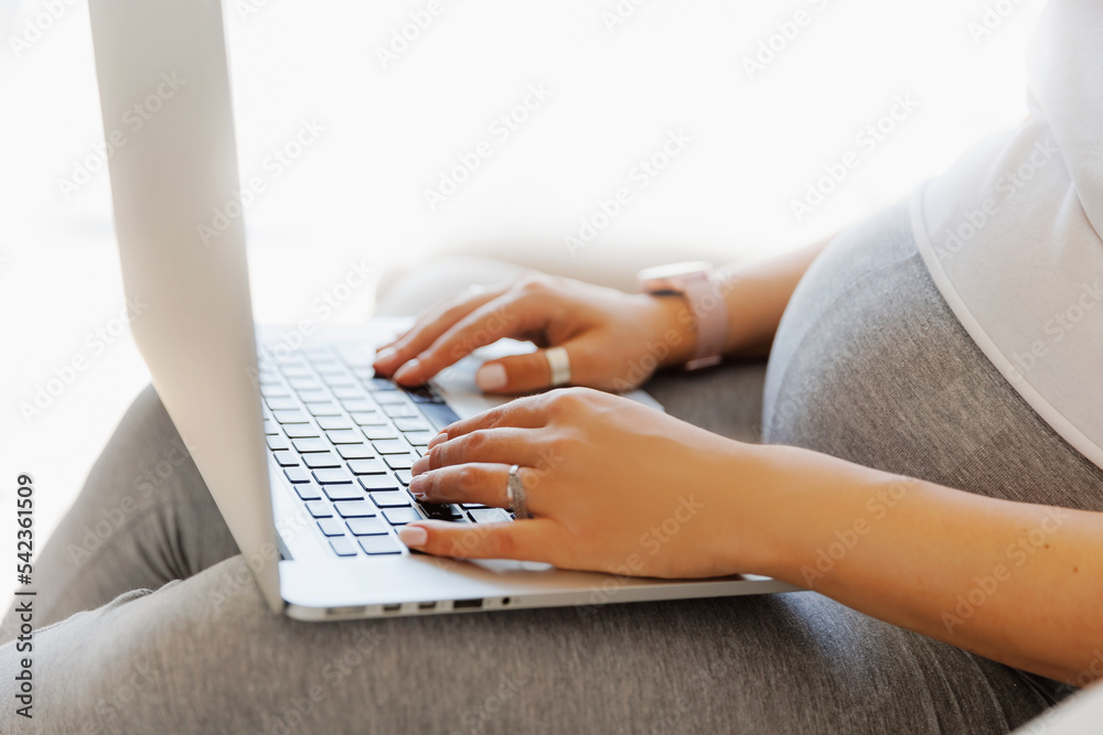 Naklejka premium Closeup hand of pregnancy woman using online laptop on sofa with sunlight