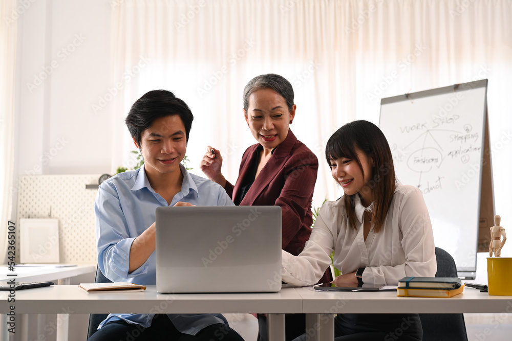 Senior female project leader explaining, discussing business plan marketing strategy with young employee