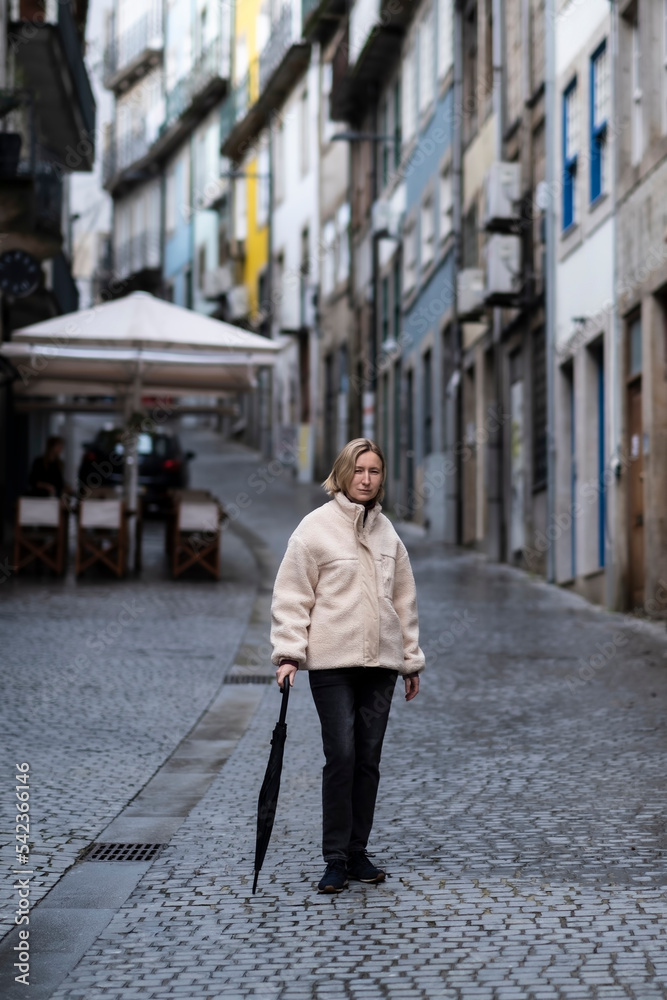 A woman with an umbrella strolling through an downtown of Porto, Portugal.