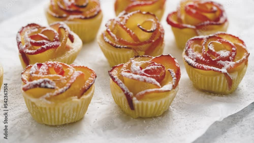 Apple rose puff pastries sprinkled with powdered on baking paper Apple rose puff pastries sprinkled with powdered on baking paper