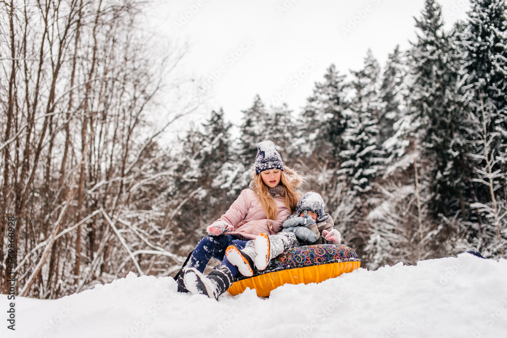 Boys and a girl are sitting in a tubing in the snow