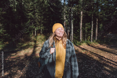 Happy woman with eyes closed hiking in forest on sunny day photo