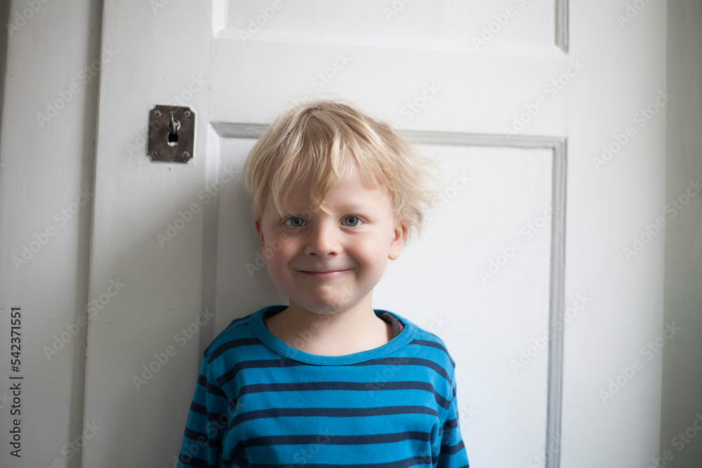 Portrait of smiling little boy in front of white door Portrait of smiling little boy in front of white door