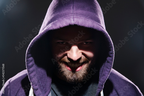 Portrait of man with hooded jacket in front of black background