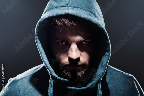 Portrait of man with hooded jacket in front of dark grey background