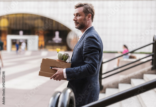 Businessman with cardboard box moving down steps