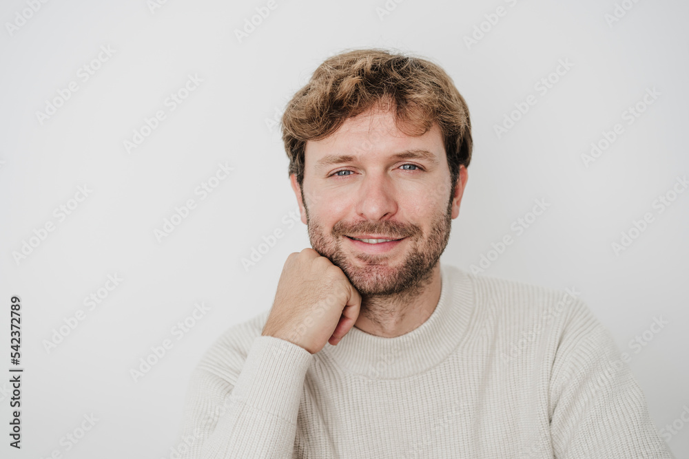 Smiling handsome businessman with hand on chin in front of white wall Smiling handsome businessman with hand on chin in front of white wall