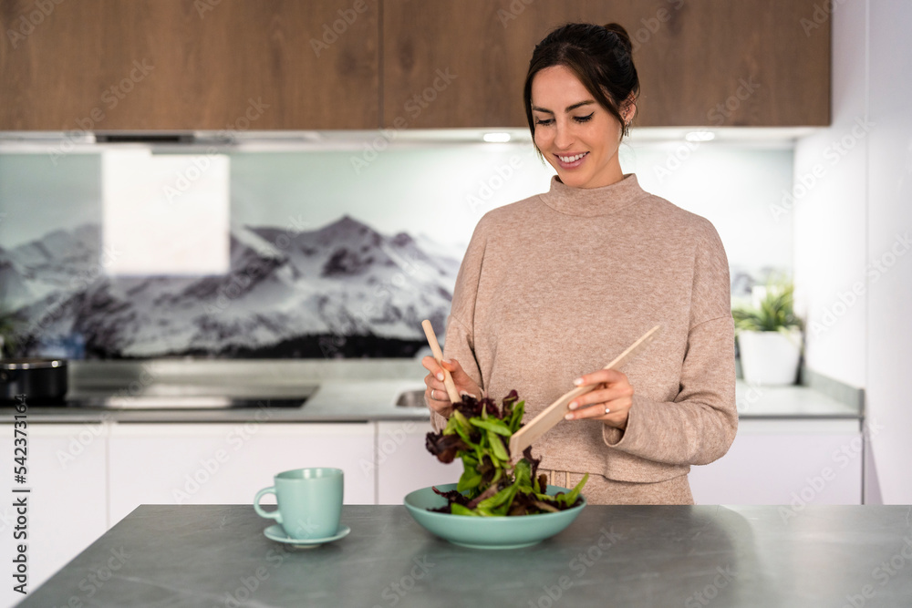Smiling young woman preparing salad at home Smiling young woman preparing salad at home