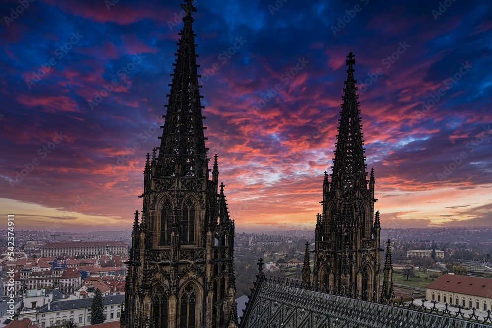 Gothic cathedral in Prague with tall elaborate towers under a vibrant blue and purple sky at sunset