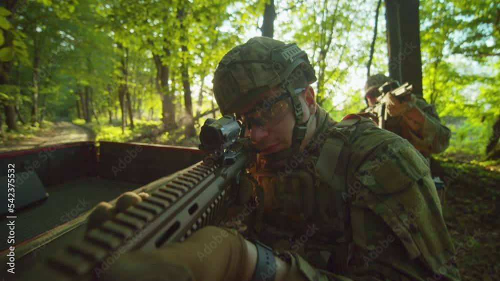 Two soldiers in camouflage uniforms with weapons slowly walk in the sunlight forest. The military sniper in the helmet is attacking and assaulting the enemy. War Two soldiers in camouflage uniforms with weapons slowly walk in the sunlight forest. The military sniper in the helmet is attacking and assaulting the enemy. War