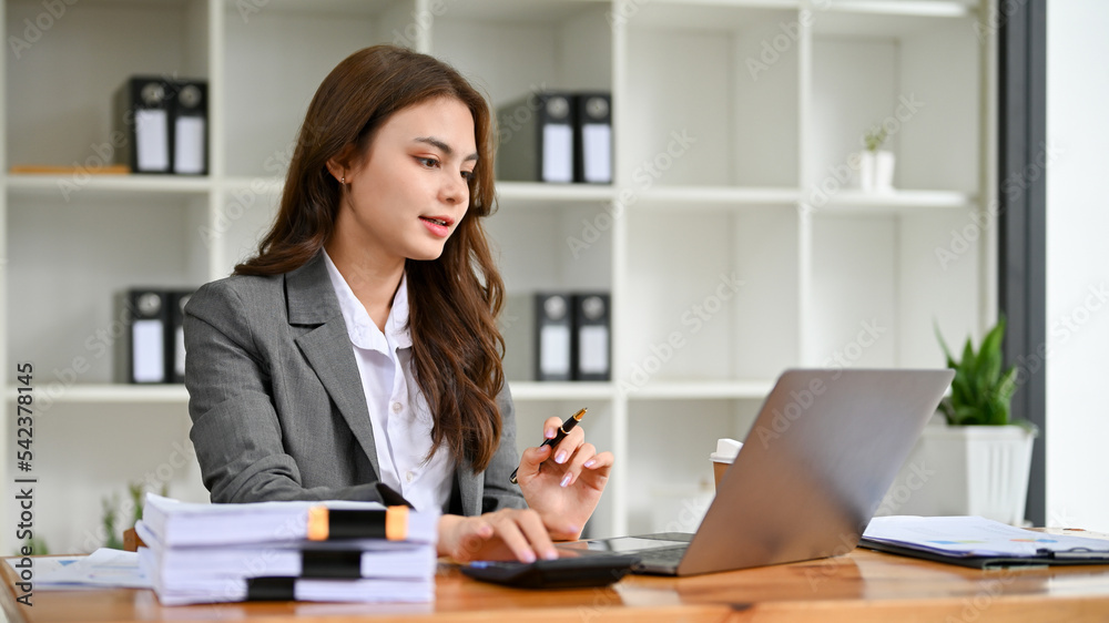 Professional Caucasian businesswoman concentrating on her tasks on laptop Professional Caucasian businesswoman concentrating on her tasks on laptop