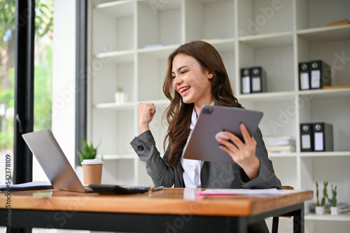 Happy and overjoyed young caucasian businesswoman looking at laptop screen