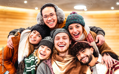 Happy multiracial guys and girls taking selfie on warm fashion clothes - Trendy life style concept with millenial people having fun together indoors on winter holidays - Warm bright filter