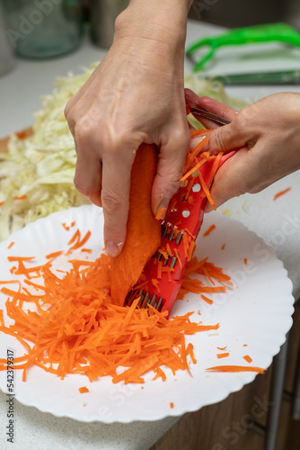 Cooking sauerkraut, cutting cabbage and carrots with a knife.