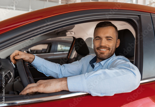 Young smiling man sitting inside her new car. Concept for car rental