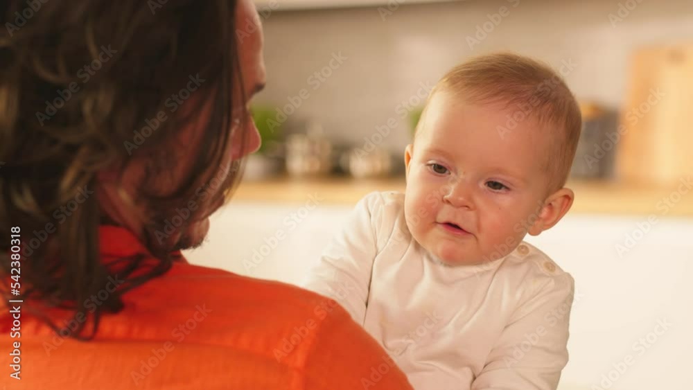 Close up smiling newborn cute baby in young father's hands. Disabled man in a wheelchair. Sunlight room apartment. Parenthood. Childhood. Slow motion Close up smiling newborn cute baby in young father's hands. Disabled man in a wheelchair. Sunlight room apartment. Parenthood. Childhood. Slow motion