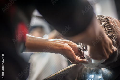 Modern urban hairdresser hairdresser washes a client hair in a professional hairdressing salon and studio. Close-up detail view