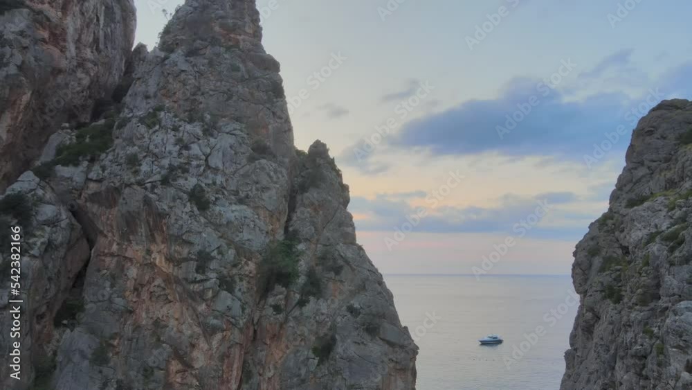 Sideways drone shot revealing Mediterranean sea and boats behind pointy rock formations at Sa Calobra, Mallorca, Spain. Sideways drone shot revealing Mediterranean sea and boats behind pointy rock formations at Sa Calobra, Mallorca, Spain.