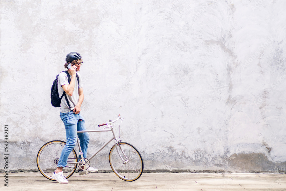 Fototapeta premium Portrait of casual hipster handsome businessman with backpack talk on smartphone while commuting riding bicycle on the street city way go to work.business travel transport bike concept