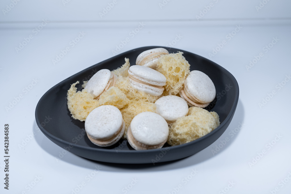 White vanilla macarons, sponge mousse cake, black dish, french dessert