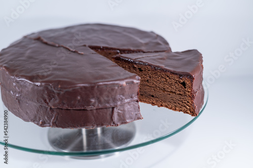 sacher torte chocolate Viena brown portion slice white background, cristal plate