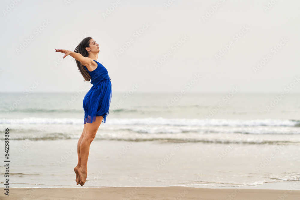 a dancer in a blue dress on the beach performing contemporary modern dance