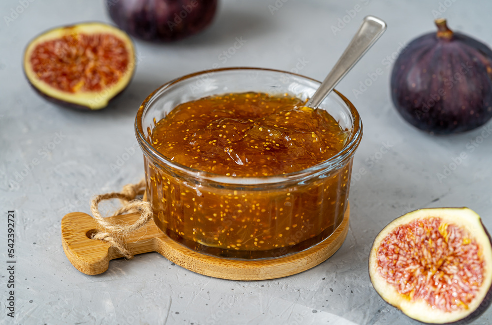 Fig jam in a glass jar with fresh fruits on gray concrete background. Close up Fig jam in a glass jar with fresh fruits on gray concrete background. Close up