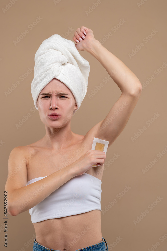Young woman doing hair removing procedures and feeling upleased Young woman doing hair removing procedures and feeling upleased