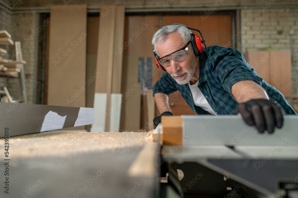 Carpenter in ear protectors working in a workshop