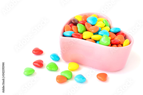 In a decorative vase are multi-colored dragee candies with chocolate filling  white isolated background.