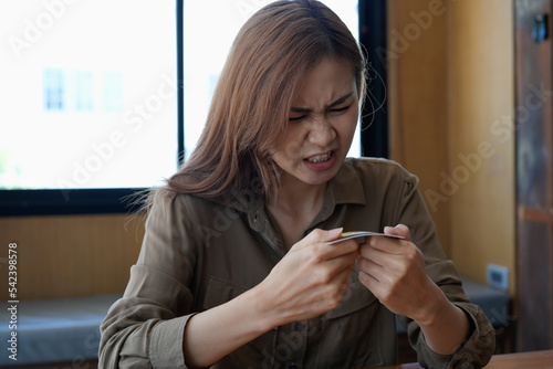 Angry young asian woman breaking a credit card with her hands.