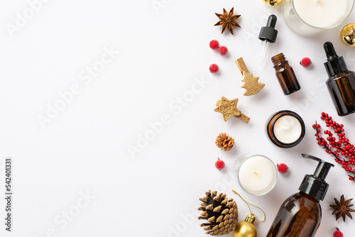 Winter skin care concept. Top view photo of cosmetic bottles candles christmas decor golden baubles decorative clips pine cone mistletoe berries and anise on isolated white background with empty space